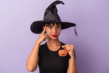 Young mixed race woman disguised as a witch isolated on purple background  pointing temple with finger, thinking, focused on a task.