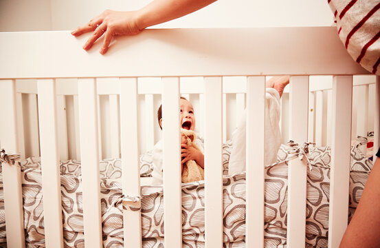 Baby hugging soft toy in crib