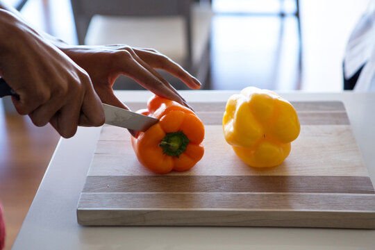 Young woman chopping orange pepper