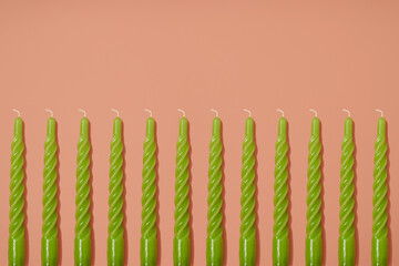 Green twisted wax candle seamless pattern on a light pastel pink background. Party layout. Copy space.