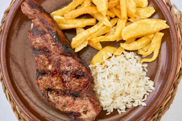 Plate of a veal cutlet with fried potatoes and rice.
