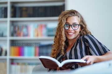 Young woman reading a book. University library and female student. Education concept