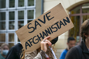 Female activist holding a cardboard sign with text Safe Afghanistan at a demonstration in Lubeck,...