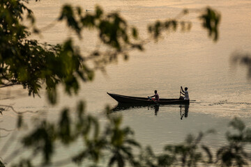 Two people paddle a canoe on smooth swamp waters during sunset in Ziwa Rhino Sanctuary, Uganda