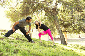 Mature running couple warming up together in park