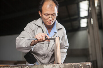 Carpenter measuring wood plank with vernier caliper in factory, Jiangsu, China