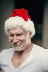 Portraite of senior man in Santa Clause hat in Gym holding a gift in his hands. Elderly age sport and fitness concept. New Years eve and Christmas background