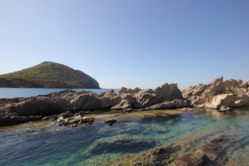 Rocks and rocky landscape visible in clear water.