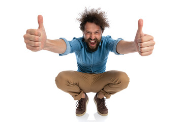 attractive casual man squatting, giving a thumbs up