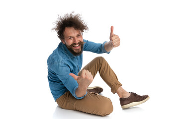 casual man sitting on the ground, giving a thumbs up