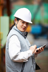Portrait of worker using smartphone at shipyard, GoSeong-gun, South Korea