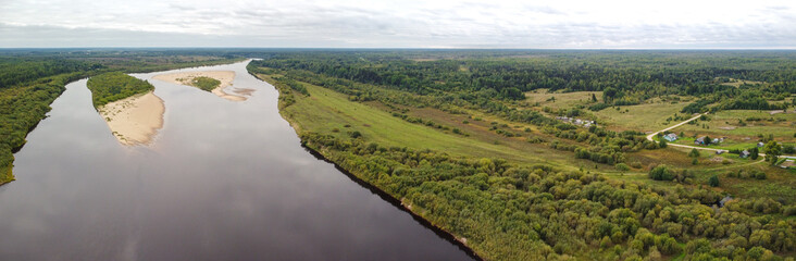 Fototapeta na wymiar Aerial panorama of a wide river in a flat area with gentle banks and sandy islands. Vaga River, Arkhangelsk Region, Russia.