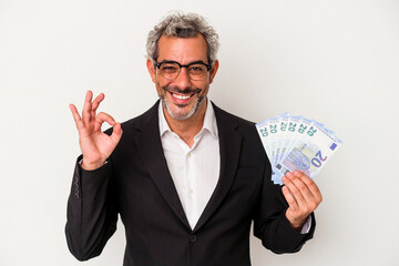 Middle age business man holding bills isolated on blue background  cheerful and confident showing ok gesture.