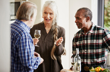 Senior friends talking in kitchen with wine