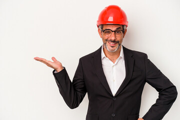 Middle age architect caucasian man isolated on white background  showing a copy space on a palm and holding another hand on waist.