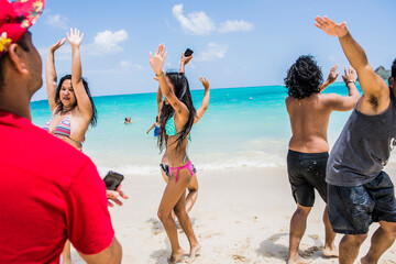 Young adult friends dancing on Lanikai Beach, Oahu, Hawaii, USA