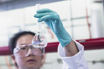 Female scientist holding up volumetric flask in lab