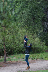 Mid adult woman holding up toddler daughter on forest path, Yosemite National Park, California, USA