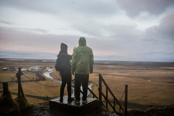 Male and female tourists taking photographs from viewing platform at Seljalandsfoss, Iceland
