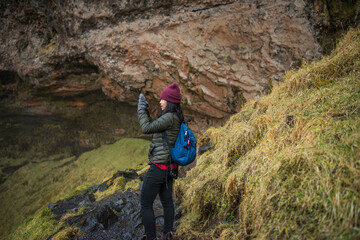 Female tourist photographing at Seljalandsfoss waterfall, Iceland