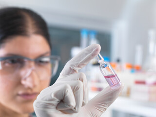 Female scientist testing medical drug ampule in laboratory