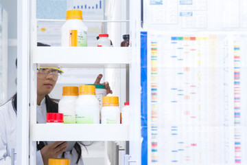 Female scientist selecting specimen jar from shelf  in laboratory