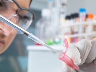 Close up of female scientist pippetting sample into eppendorf tube for analysis in laboratory