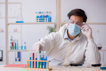 Young male chemist working at the lab during pandemic