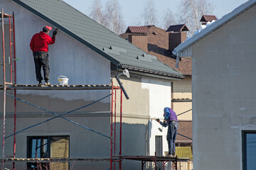 close up details of painting walls, industrial worker using roller and other tools for painting walls of new house
