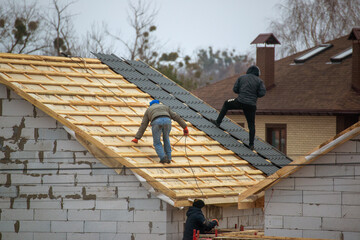 a professional roofer with electric screwdriver covers repairs the roof