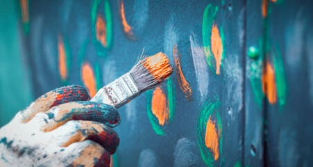 A hand holding a paint brush and painting a wall