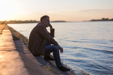 lonely man sitting on the river bank