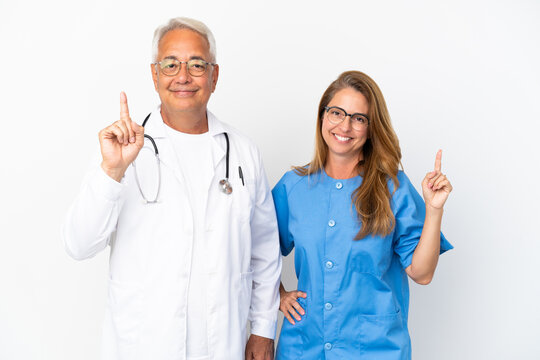 Middle age doctor and nurse isolated on white background showing and lifting a finger in sign of the best