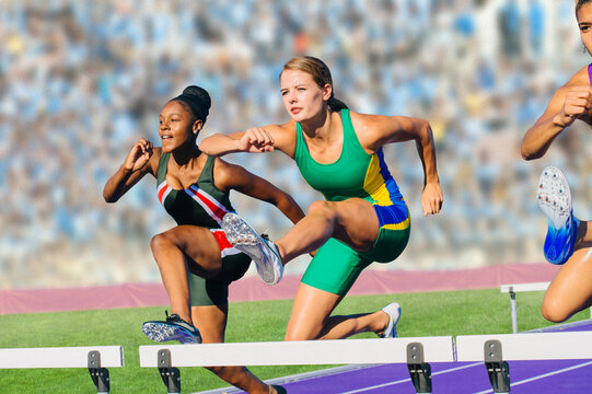 Runners jumping over hurdle on track