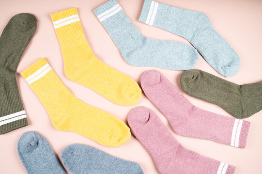 Various men's socks with stripes on a pink background, top view