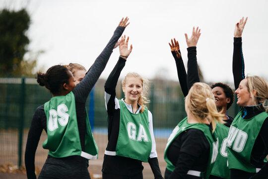 Female netball team giving high fives on netball court