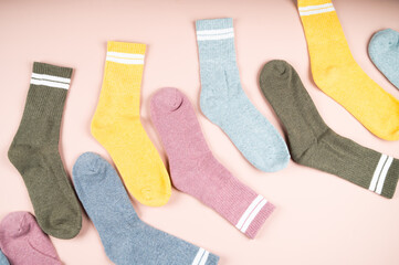 Various men's socks with stripes on a pink background, top view