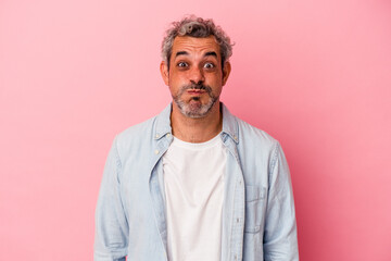 Middle age caucasian man isolated on pink background  blows cheeks, has tired expression. Facial expression concept.