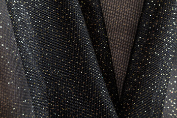 folded black neoprene fabric with gold sequins