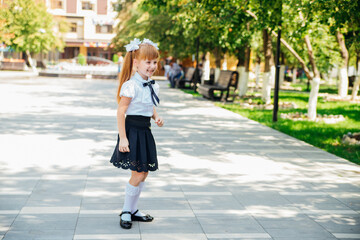 A little girl elementary school student is having fun walking down the street.The child happily goes to school.