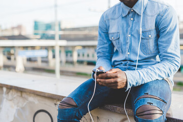 Cropped view of man wearing headphones using smartphone, Milan, Italy