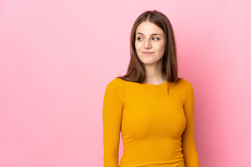 Obraz premium Young caucasian woman isolated on pink background having doubts while looking side