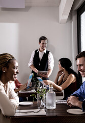 Waiter serving diners in restaurant, waiter using digital tablet