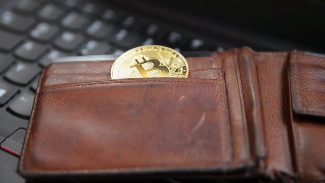 Closeup of a golden bitcoin medal on a black keyboard.