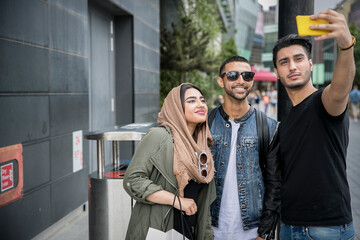 Naklejka premium Three friends in street, taking selfie with smartphone