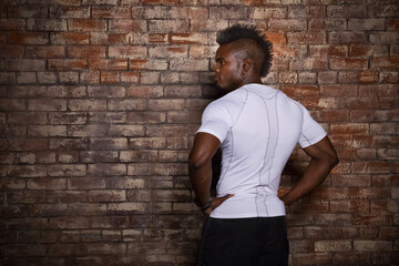 Young man with mohawk, standing in front of brick wall