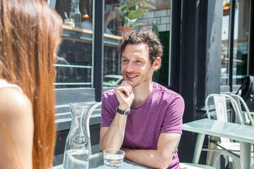 Mid adult couple chatting at city sidewalk cafe