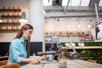 Fototapeta premium Female customer typing on laptop in cafe