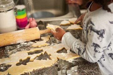 Girl cutting cookie dough with cookie cutters