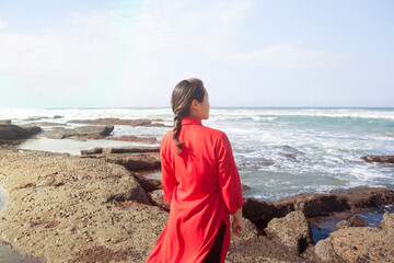 Woman wearing red dress, standing on rocks, looking at sea view, South Africa